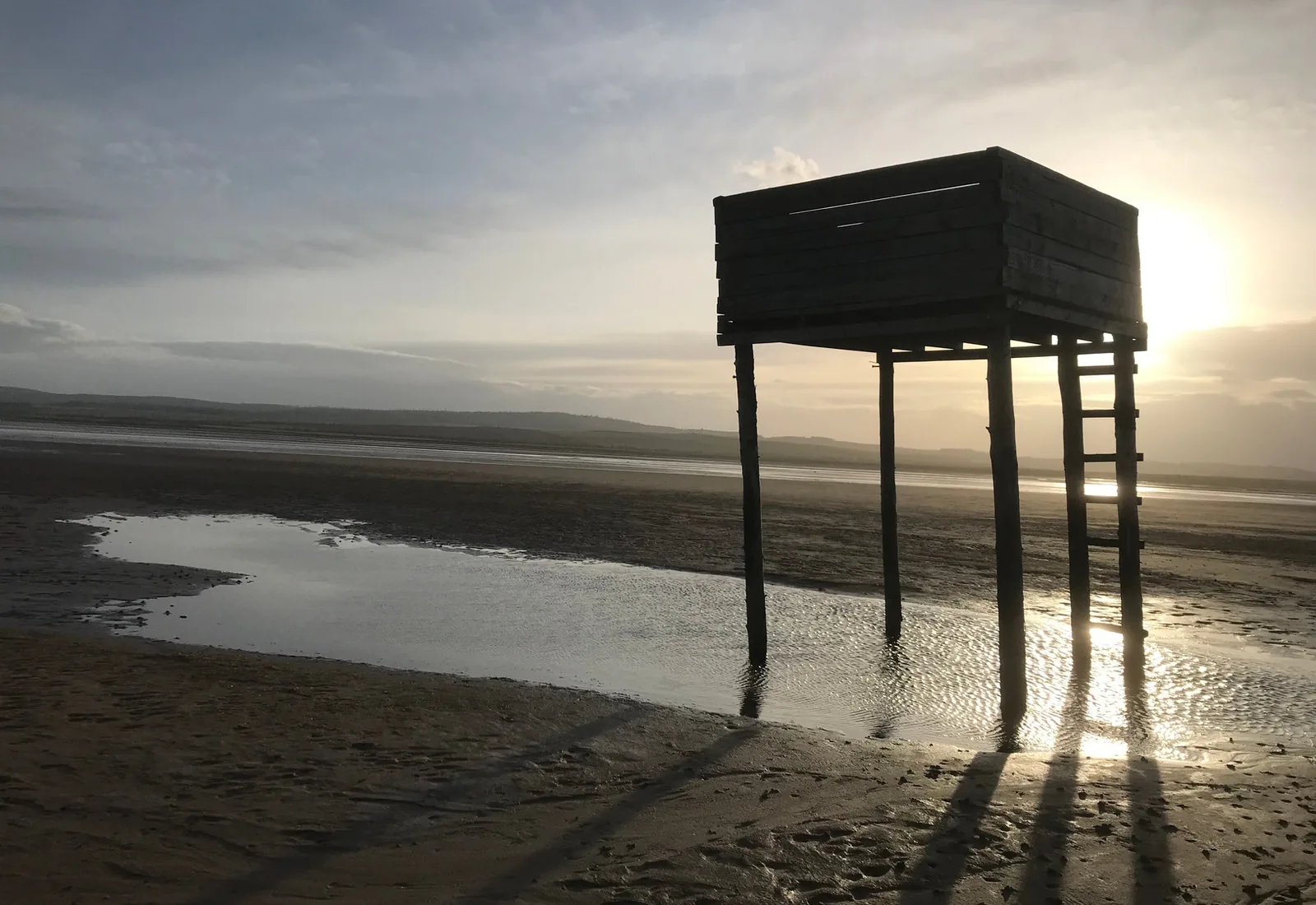 The timber pilgrims' refuge box standing on stilts on the tidal sands to Holy Island at low sun